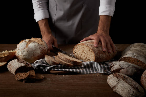istock cropped image of baker in apron cutting bread on sackcloth on wooden table 992012820