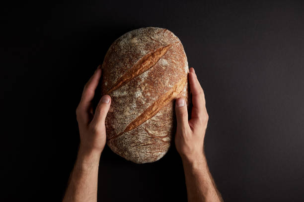 istock cropped shot of man holding bread on dark tabletop 992016476