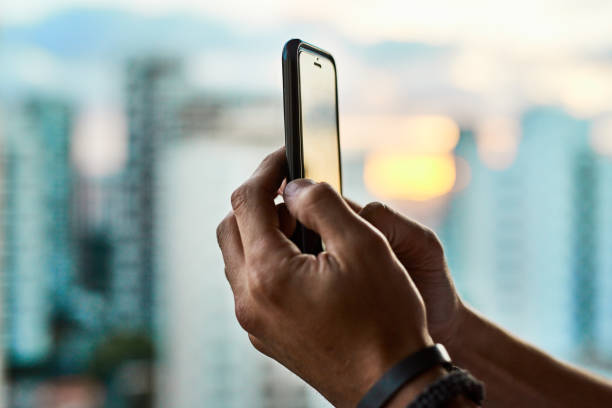 Cropped shot of an unrecognizable man taking a photo of the city with his cellphone outside