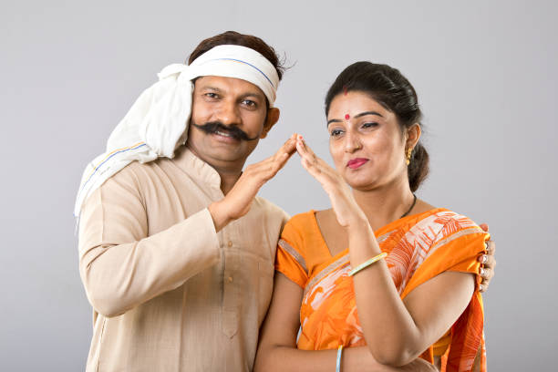 Portrait of Indian couple in traditional clothing gesturing house sign