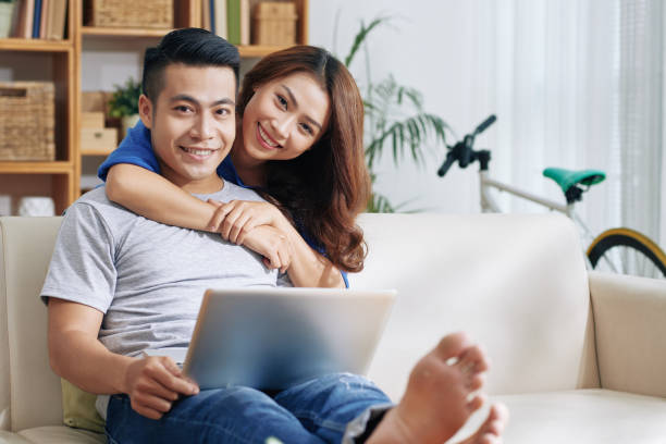 istock Smiling Asian couple with laptop on sofa 992033166