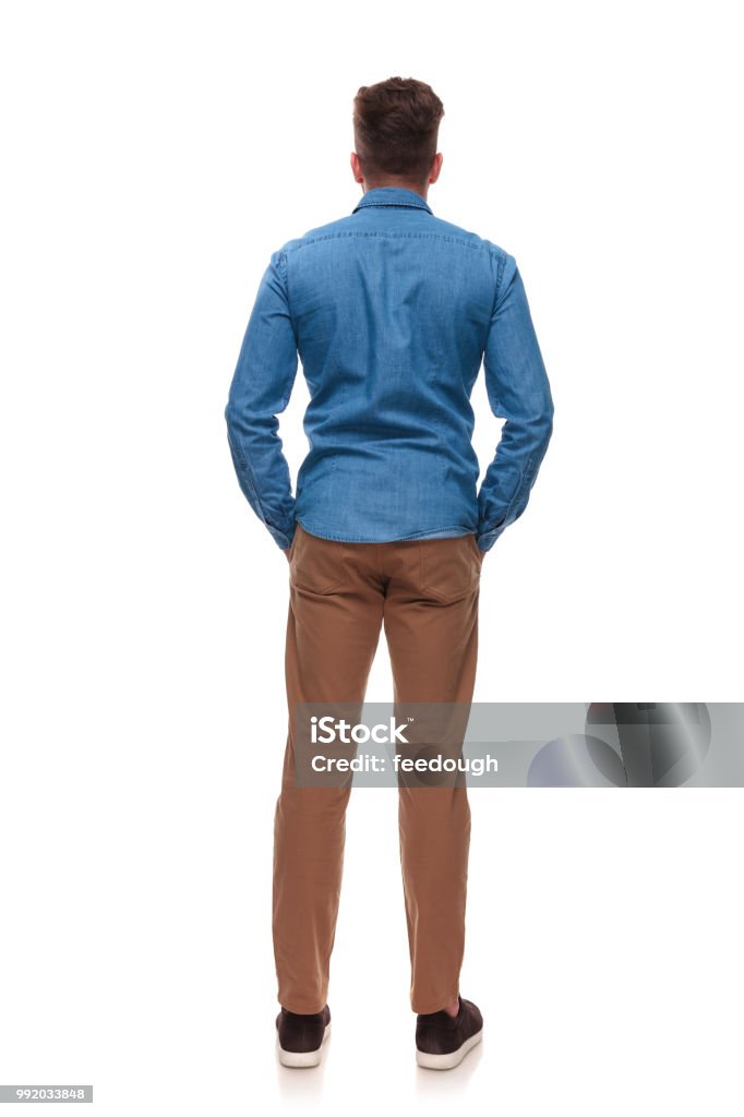 rear view of casual man standing with hands in pockets rear view of casual man standing on white background with hands in pockets Rear View Stock Photo