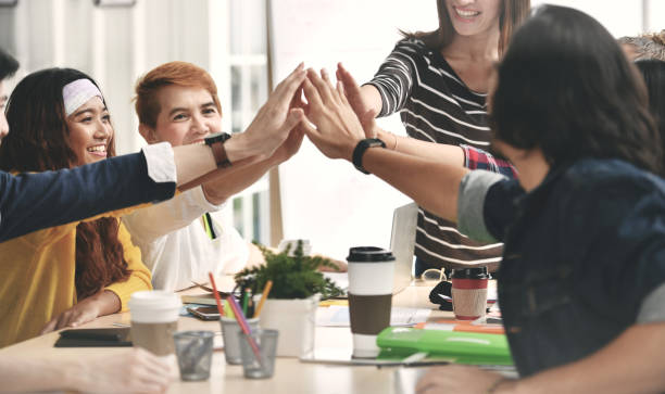istock Group of businesspersons tapping hands / high five 992034044