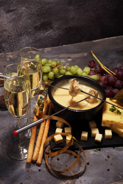 istock Gourmet Swiss fondue dinner on a winter evening with assorted cheeses on a board alongside a heated pot of cheese fondue 992034208