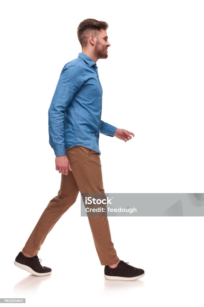 side view of handsome casual man walking side view of handsome casual man wearing a blue shirt walking on white background Walking Stock Photo