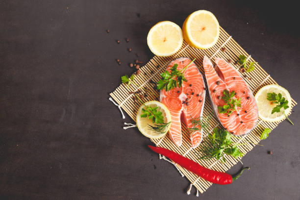 istock Salmon steaks with lemon and spices on black background with copy space text. 992039040