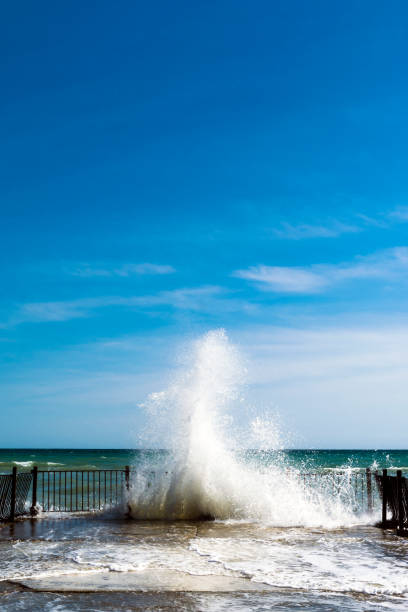 istock Sea water splashes at old pier on sunny day 992046156