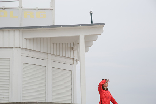 Woman in red jacket standing on the wooden lifeguard tower station