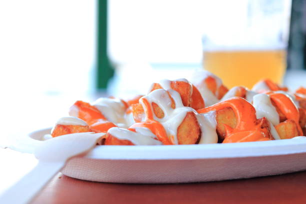 Patatas Bravas typical spanish dish in a bar near the beach, during summer,fried potatoes with spicy sauce and pepper.