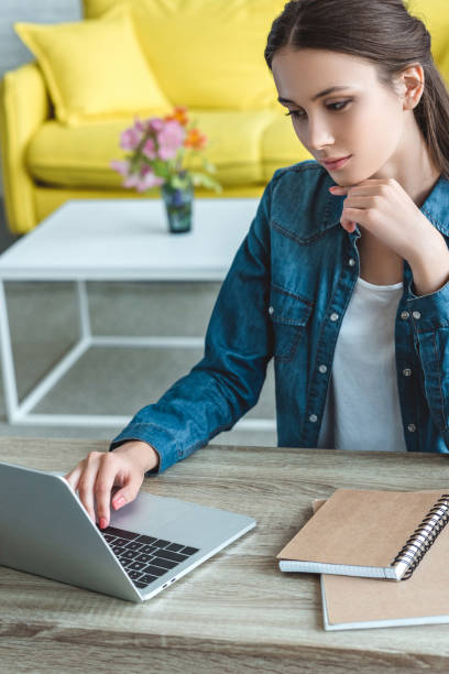 istock focused girl using laptop while sitting at wooden table at home 992051514