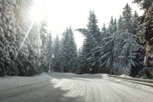 istock View from a car riding through snow covered winter road curve, lit by strong sun backlight - dangerous driving conditions. 992070126