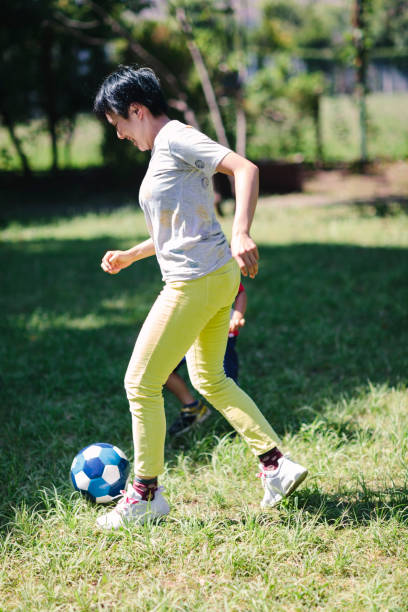 istock Mother and son playing soccer in public park 992071452