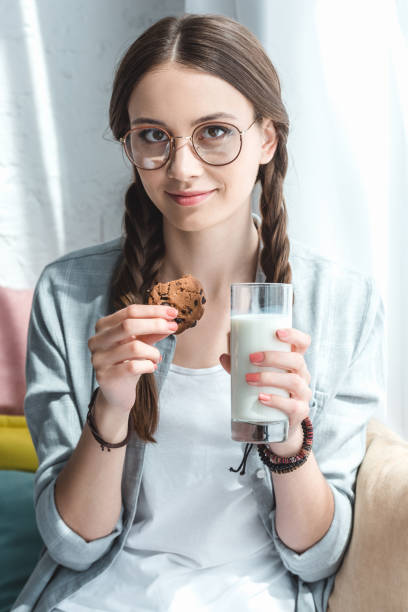 красивая девушка-подросток с печеньем и молоком в стекле - beauty beautiful braids dairy product стоковые фото и изображения