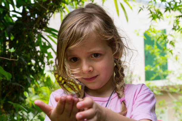 istock Low Angle View of a Child With Butterfly on Fingertips 3 992089314