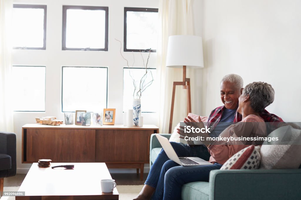 Älteres Paar auf Sofa sitzen zu Hause mit Laptop Shop Online - Lizenzfrei Seniorenpaar Stock-Foto