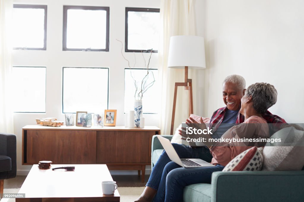 ソファーに座っていた自宅ショップにラップトップを使用してオンライン シニア カップル - 年配のカップルのロイヤリティフリーストックフォト