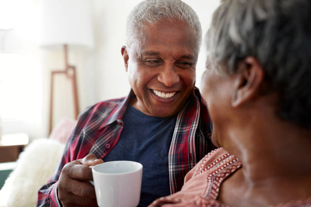 istock Senior Couple Sitting On Sofa At Home Relaxing With Hot Drink 992097020