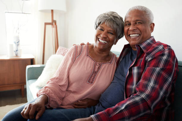 Portrait Of Loving Senior Couple Relaxing On Sofa At Home Portrait Of Loving Senior Couple Relaxing On Sofa At Home african american couple stock pictures, royalty-free photos & images