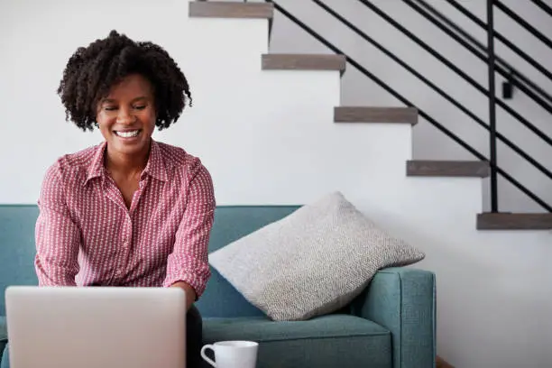 Photo of Woman Sitting On Sofa At Home Using Laptop Computer