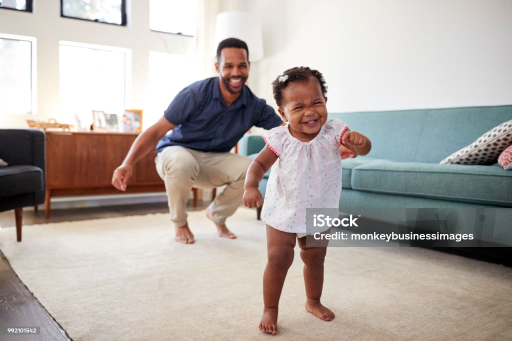 Hija de bebé bailando con el padre en el salón en casa - Foto de stock de Bebé libre de derechos