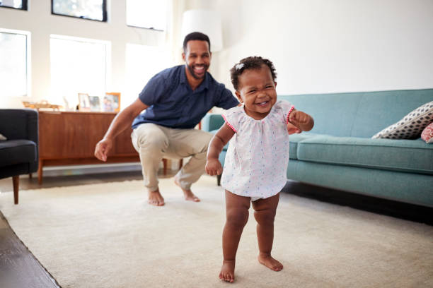 Baby Daughter Dancing With Father In Lounge At Home Baby Daughter Dancing With Father In Lounge At Home first steps stock pictures, royalty-free photos & images