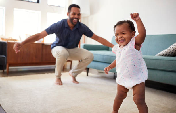 Baby Daughter Dancing With Father In Lounge At Home Baby Daughter Dancing With Father In Lounge At Home first steps stock pictures, royalty-free photos & images