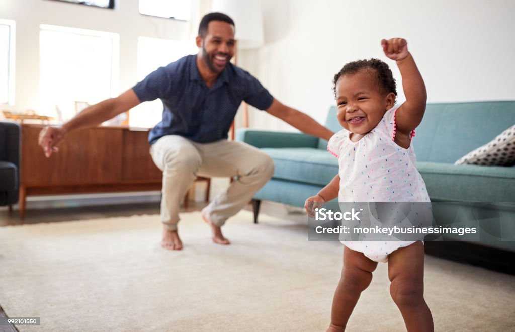 Filha de bebê dançando com o pai na sala de estar em casa - Foto de stock de Bebê royalty-free