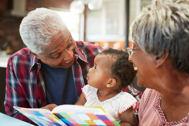 großeltern buch mit baby enkelin zu hause - grandparent family reading inside of stock-fotos und bilder