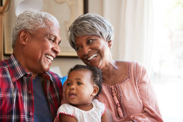 abuelos sentados en el sofá con nieta bebé en casa - abuelo y bebe fotografías e imágenes de stock