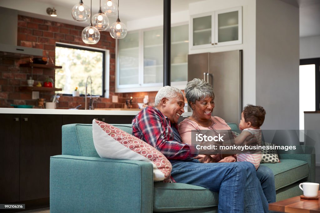 Grands-parents assis sur le canapé avec la petite-fille de bébé à la maison - Photo de Troisième âge libre de droits