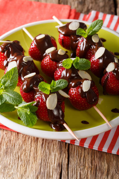 istock Ripe strawberries decorated with chocolate, mint and almonds close-up. vertical 992106574