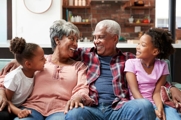 istock Grandparents Relaxing On Sofa At Home With Granddaughters 992107340