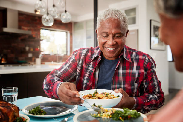 Senior Couple Enjoying Meal Around Table At Home Senior Couple Enjoying Meal Around Table At Home mouth full stock pictures, royalty-free photos & images