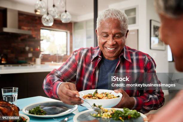 Senior Couple Enjoying Meal Around Table At Home Stock Photo - Download Image Now - Eating, Senior Adult, Food