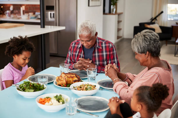 istock Grandparents Praying Before Meal At Home With Granddaughters 992108268