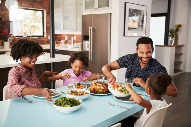familia disfrutando de comida alrededor de la mesa en casa juntos - cena fotografías e imágenes de stock