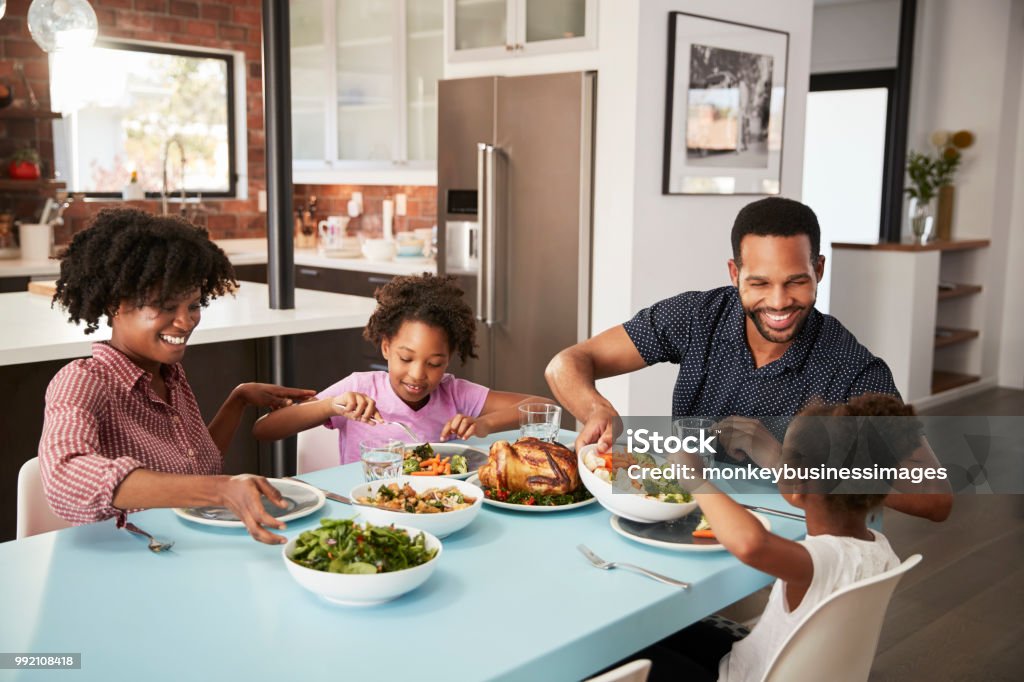 Family Enjoying Meal Around Table At Home Together Family Stock Photo