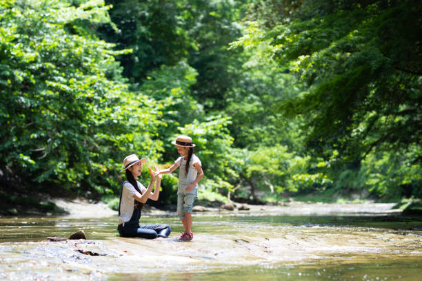 istock Mother and daughter playing in the river 992111478