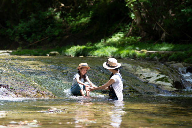 istock Mother and daughter playing in the river 992111840