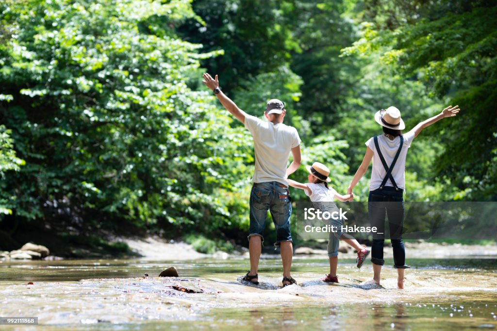 Padre y madre e hija juegan en el río - Foto de stock de Familia libre de derechos