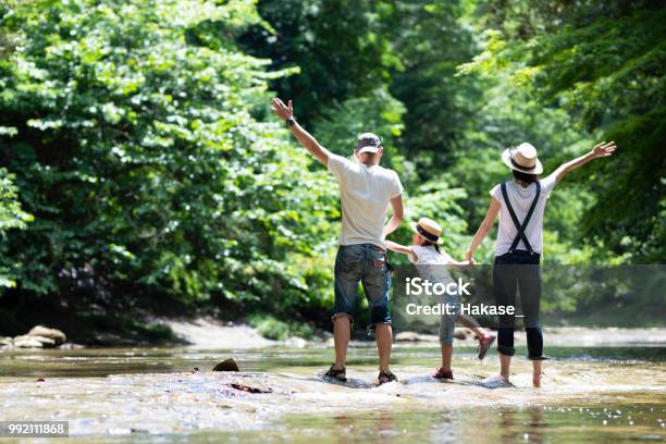 Photo libre de droit de Père Et Mère Et La Fille Jouent Dans La Rivière banque d'images et plus d'images libres de droit de Famille - Famille, Camping, Nature