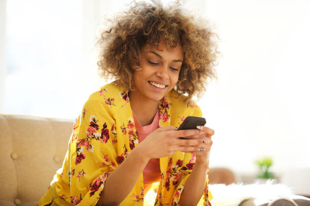 istock beautiful african american woman using cellphone at home 992112550