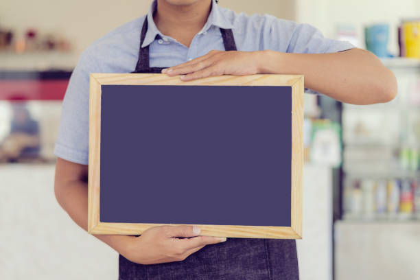istock Asian waiters showing food menu with wood frame in restaurant.; 992118942