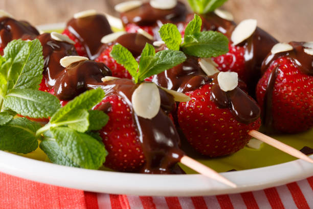 istock Strawberry on skewers with chocolate icing, mint and almonds macro. horizontal 992125368