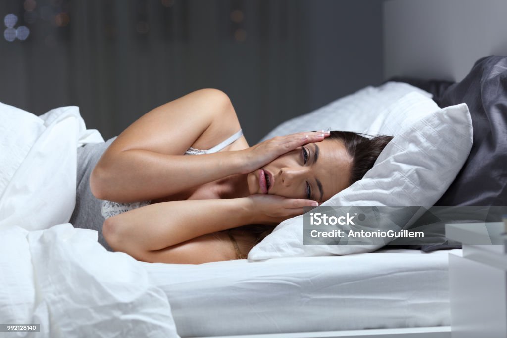 Desperate girl suffering insomnia trying to sleep Desperate girl suffering insomnia trying to sleep in a bed at home in the night Sleeping Stock Photo