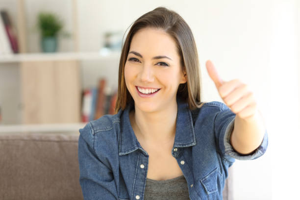 istock Happy woman gesturing thumbs up on a couch 992128250