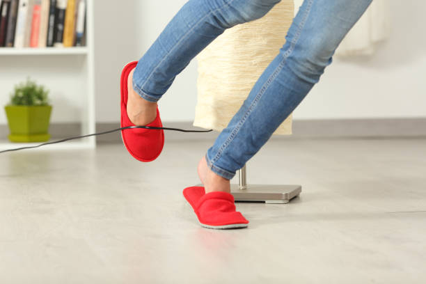 tropezar con un cable eléctrico en la casa de la mujer - tropezar caer fotografías e imágenes de stock