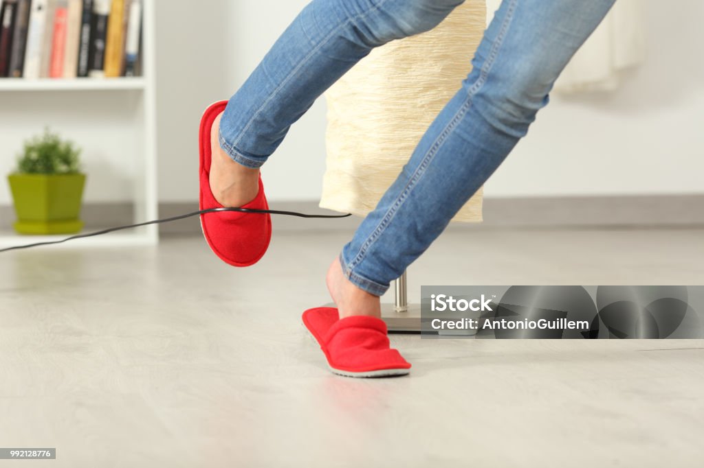 Woman stumbling with an electrical cord at home Close up of a woman legs stumbling with an electrical cord at home Misfortune Stock Photo