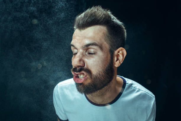 istock Young handsome man with beard sneezing, studio portrait 992130356