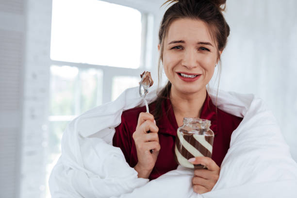 istock Depressed woman eating chocolate spread sitting in bed 992133886